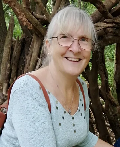 Grandma Picton, smiling, sitting in a woodland den